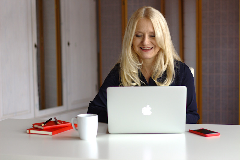 Netzgenuss - Birgit Haase sitzt vor dem Laptop und lächelt. Das Internet, wie es Dir gefällt!